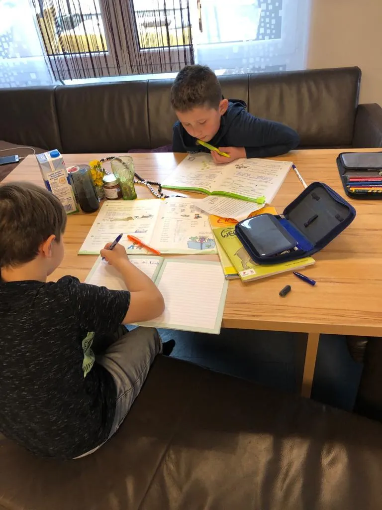 Zwei Kinder machen gemeinsam Hausaufgaben am Tisch