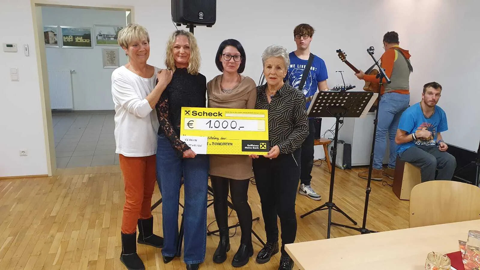 Vier Frauen halten einen Spendenscheck in einem Veranstaltungsraum